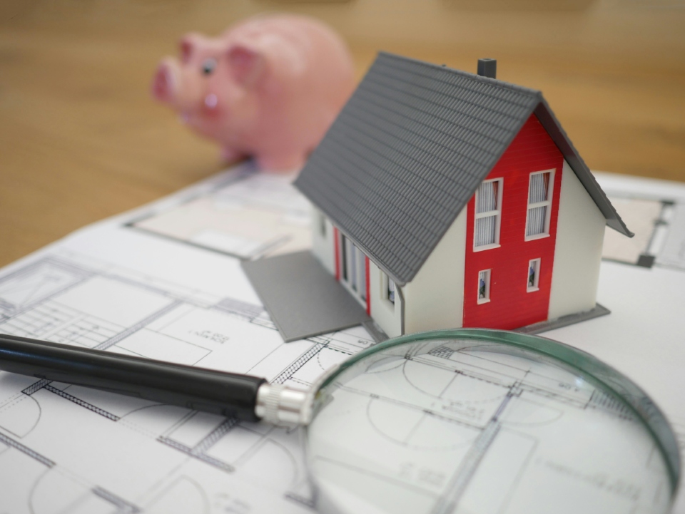 Model house with magnifying glass and plans.