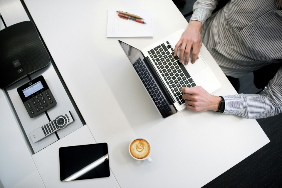 Person working on laptop with coffee.